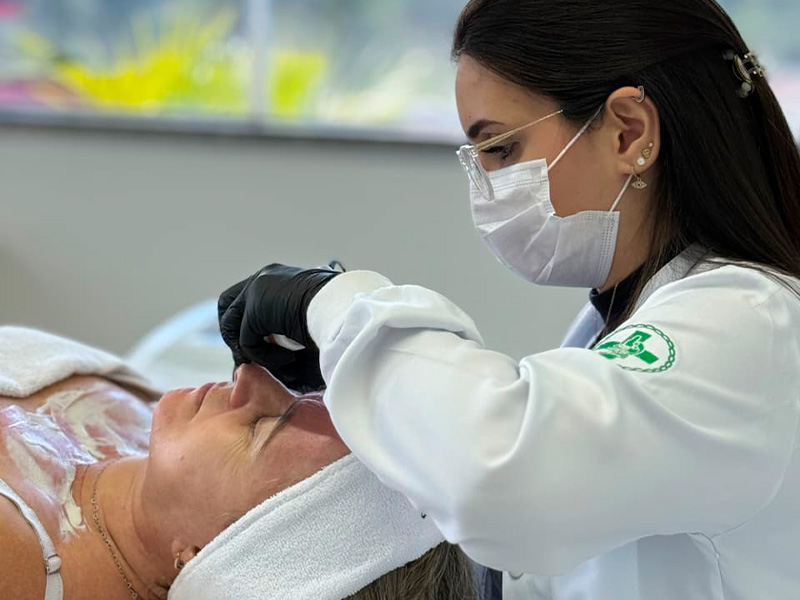 Medica esteta realizando procedimento de limpeza de pele em cliente